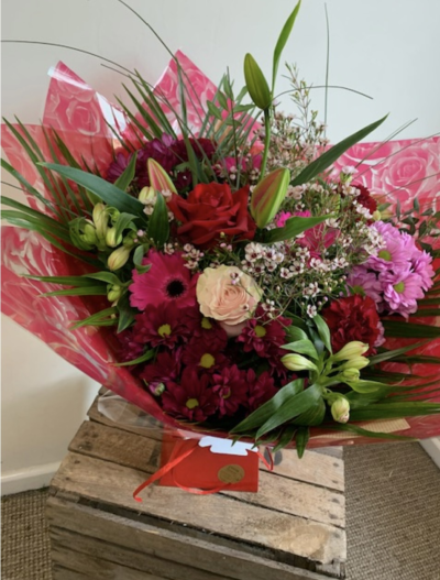 Valentines Florist Choice hand tied bouquet - A hand tied bouquet of valentines flowers, including a beautiful long stem large red rose. Presented in red wraps and a red box.
